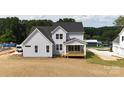 View of the back exterior featuring a charming covered porch perfect for relaxation, set against a backdrop of lush greenery at 4251 Candlewood Dr, Sherrills Ford, NC 28673