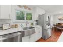 Farmhouse sink and stainless steel appliances in a white kitchen at 13470 Austin Rd, Locust, NC 28097