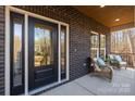 Brick front porch with wicker chairs and a black front door at 5528 Brickstone Dr, Charlotte, NC 28227