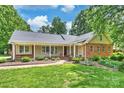 Charming ranch-style home featuring a welcoming front porch, lush lawn, and manicured landscaping at 7135 Folger Dr, Charlotte, NC 28270