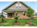 New construction home featuring a brick exterior, an outdoor patio, a grassy yard, and young trees at 9657 Liberty Hill Dr, Mint Hill, NC 28227