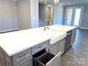 Kitchen island with white countertop, gray cabinets, a farmhouse sink and built in trash receptacle at 9657 Liberty Hill Dr, Mint Hill, NC 28227