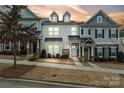 Three-story townhome with gray and white siding, a green door, and stone accents at dusk at 12515 Bryton Ridge Pkwy, Huntersville, NC 28078