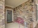 Close-up of the front porch featuring a decorative wreath, stone wall, and a charming pink bench at 1255 Restoration Dr, Waxhaw, NC 28173