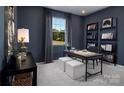 Dark-blue home office with built-in shelving, desk, and two ottomans at 2526 Crimson Way, Monroe, NC 28112