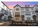 Three-story townhome with gray and white exterior, brick accents, and a charming front porch at sunset at 6027 Towering Oaks Dr, Charlotte, NC 28205