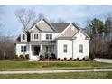 Two story home with white brick and taupe accents, front porch, and landscaped yard at 2010 Belle Grove Dr, Marvin, NC 28173