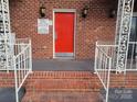 Apartment building entrance featuring a bright red door with brick steps and wrought iron railings at 2121 Carriage Woods Ln, Kannapolis, NC 28081