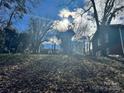 Sloped backyard with leaf-covered ground and trees at 323 Whispering Pines Dr, Charlotte, NC 28217