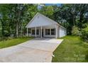 A quaint house with a covered porch and a long concrete driveway on a sunny day at 408 N Boyd St, Gastonia, NC 28052