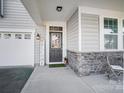 Front entrance with a dark gray door, stone accents, and welcome sign at 19117 Hawk Haven Ln, Charlotte, NC 28278