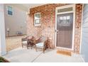 Brick front porch with two wicker chairs and a welcome mat at 3936 Rothwood Ln, Harrisburg, NC 28075