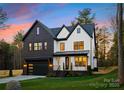 Striking two-story home with a modern black and white facade, black garage door, and manicured lawn at 10605 S Hampton Dr, Charlotte, NC 28227