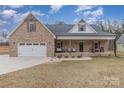 Brick home with a covered porch and a two-car garage, complemented by a well-maintained lawn at 1076 Furnace Rd, Iron Station, NC 28080
