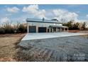 Gray metal barn-style home with triple garage doors and covered porch at 219 Mock Mill Rd, Statesville, NC 28677