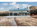 Gray metal barn-style home with triple garage doors and covered porch at 219 Mock Mill Rd, Statesville, NC 28677