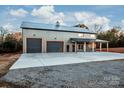 Gray metal barn-style home with triple garage doors and covered porch at 219 Mock Mill Rd, Statesville, NC 28677