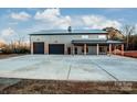 Gray metal barn-style home with triple garage doors and covered porch at 219 Mock Mill Rd, Statesville, NC 28677