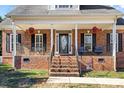 Brick front porch with hanging plants, black railings, and steps leading to the front door at 304 Forbes Ct, Clover, SC 29710