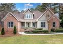 Charming home with a lush landscaped yard, inviting front porch, and brick and siding facade at 302 Mccrary Rd, Mooresville, NC 28117
