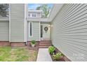 Close-up of home's entrance featuring light green siding, a decorative wreath, and well-maintained landscaping at 10912 Treebark Dr, Charlotte, NC 28226