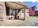 Inviting front porch with stone flooring, entry door, and American flag at 14818 Long Iron Dr, Huntersville, NC 28078