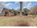 Charming single-story brick home with a cozy front porch and mature trees in a leafy side yard at 3050 Wilkesboro Hwy, Statesville, NC 28625