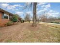 The side yard is grassy and has a charming brick house with mature trees at 3050 Wilkesboro Hwy, Statesville, NC 28625