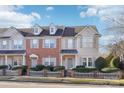 Two-story townhome with brick and siding exterior, featuring a gray door and a white picket fence at 6033 Creft Cir, Indian Trail, NC 28079