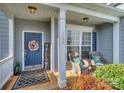 Inviting front porch with stylish seating, a 'welcome' sign, and a wreath on a dark blue front door at 265 Sutro Forest Nw Dr, Concord, NC 28027