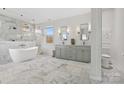 Spa-like bathroom with soaking tub, double vanity, and marble tile at 8788 Potter Rd, Matthews, NC 28104