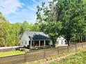 A charming home with a cozy porch, surrounded by trees and a well-maintained fence at 888 Brevard Place Rd, Iron Station, NC 28080