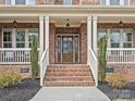 Welcoming front porch with brick stairs leading to the wood door, complemented by white columns at 120 Trelawn St, Fort Mill, SC 29715