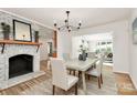 Open dining room with fireplace, chandelier, wood floors, and access to other living spaces at 3828 Chandworth Rd, Charlotte, NC 28210