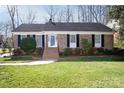 Charming brick home with manicured lawn, black shutters and inviting front porch at 3828 Chandworth Rd, Charlotte, NC 28210