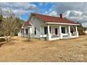 White house with red roof and a spacious front porch at 6963 Kershaw Camden Hwy, Kershaw, SC 29067