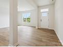 Bright and open living room with wood-look flooring, a large window, and a modern white front door at 10119 Mamillion Dr, Huntersville, NC 28078