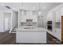 Modern white kitchen with large island, stainless steel appliances, and mosaic backsplash at 1182 Lost Cove Rd, Indian Land, SC 29707