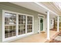 Inviting front porch of home with white pillars and green siding at 17521 Cambridge Grove Dr, Huntersville, NC 28078