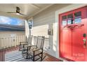 Inviting front porch with rocking chairs, red door entry, and decorative rug at 2408 Rozzelles Ferry Rd, Charlotte, NC 28208