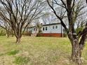 Single-story home with light gray siding, brick foundation, and a covered porch, framed by large trees in the front yard at 400 E 27Th St, Kannapolis, NC 28083