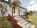 Close up of the front porch with wooden support beams, brick foundation and concrete steps leading up to the front door at 400 E 27Th St, Kannapolis, NC 28083