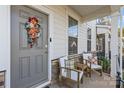 Gray front door with wreath, two wooden chairs, and sidelights at 4020 Harmony Hills Dr, Matthews, NC 28104