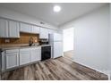 Efficient kitchen with white cabinets, black appliances, and wood-look floors at 7151 Stonington Ln, Charlotte, NC 28227