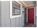 Condo entrance with red door, gray siding, and a window at 7608 Woods Ln # 12, Cornelius, NC 28031