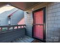 Inviting condo entrance with a vibrant red door, gray siding, and cozy outdoor area at 9037 J M Keynes Dr # 23, Charlotte, NC 28262