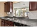 Practical kitchen with stainless steel dishwasher, dark cabinets, and view to the living area at 9037 J M Keynes Dr # 23, Charlotte, NC 28262
