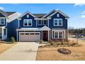 Two-story blue house with red door, neutral garage door, and landscaping at 14247 Canemeadow Dr, Charlotte, NC 28278