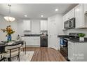 Modern kitchen with white cabinets, black appliances, and dining area at 275 Broad Sw Dr, Concord, NC 28025