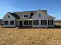 Modern farmhouse exterior boasts white siding, dark windows, and a spacious yard at 2906 Lathan Rd, Monroe, NC 28112